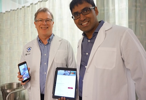 two people in lab coats holding up a tablet