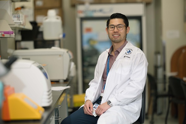 A man sits at a lab bench