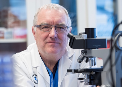 Dr. John Bell in front of a microscope