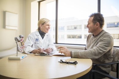 A female doctor sits at a table with a male patient.