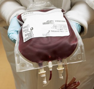 a person in a lab coat holding a blood bag