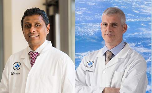 two people in white lab coats standing in front of a blue sky